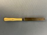 a knife with a yellow handle sitting on top of a table