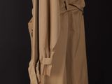 a woman in a trench coat standing in front of a black background