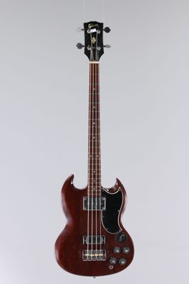 un gros plan sur une guitare basse rouge suspendue à une corde