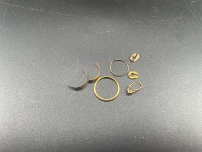 un gros plan sur une paire de bagues en or posées sur une surface noire