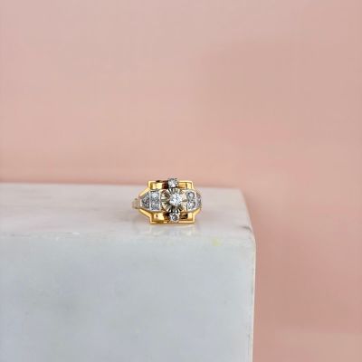 un gros plan d'une bague en or et diamants posée sur un bloc de marbre