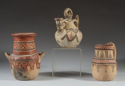 trois vases décorés de motifs sont posés sur un socle
