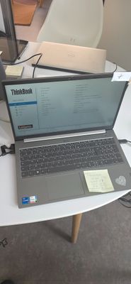 un ordinateur portable posé sur une table, avec un bloc-notes dessus