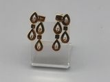 une paire de boucles d'oreilles en or et diamants posée sur un présentoir transparent