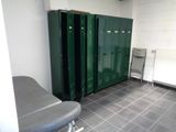 several green lockers in a room with a bench and a radiator