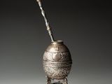 un vieux vase en argent d'où sort un bâton