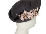 un chapeau noir orné de fleurs, posé sur la tête d'un mannequin