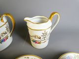 quatre pièces de vaisselle en porcelaine posées sur une table, avec une tasse et une soucoupe