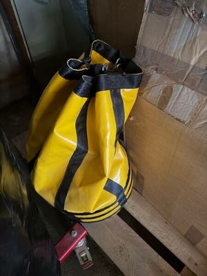 un sac jaune et noir posé sur une palette à côté d'une pile de cartons