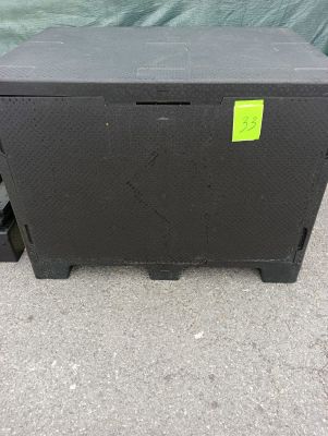 une boîte noire sur laquelle est collé un autocollant jaune, posée par terre
