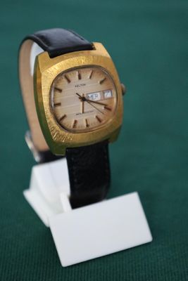 a watch that is sitting on a stand on a green surface