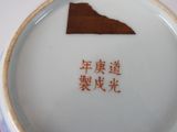 a white plate with chinese writing on it and a brown piece of paper in the middle