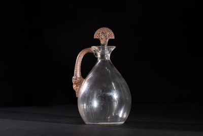 an old glass jug with a handle on a black surface