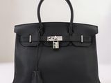 un sac à main en cuir noir posé sur une table blanche
