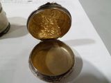 une boîte en argent avec un couvercle en or posée sur une table
