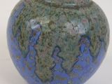 un vase bleu et vert posé sur une surface blanche