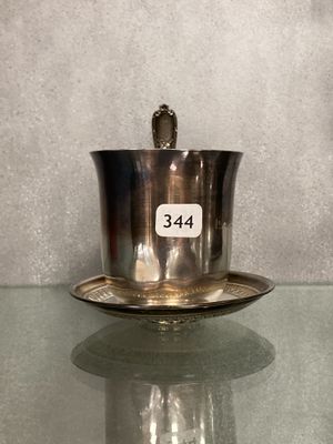 a silver cup and saucer sitting on a glass table