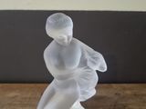 a glass figurine of a woman sitting on a table