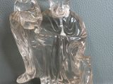 une figurine en verre représentant un homme assis sur une chaise