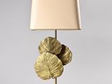 gold leaf table lamp with a beige shade on a white base