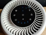 a white fan sitting on top of a table next to a cup of coffee
