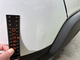someone is measuring the height of a car ' s bumper with a ruler