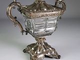 un vase en argent muni d'un couvercle et posé sur un socle