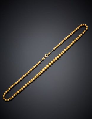 a gold beaded necklace on a black background