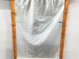 un miroir avec un cadre en bambou accroché au mur