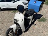 un scooter blanc garé sur un parking, à côté d'autres voitures