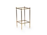une table d'appoint en laiton avec un plateau en verre, sur fond blanc
