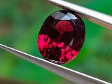 un gros plan d'un diamant rouge tenu par une pince