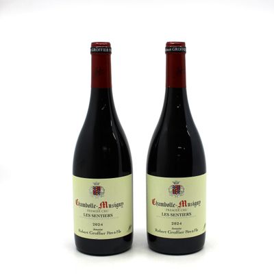 two bottles of red wine sitting next to each other on a white surface