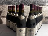 several bottles of wine are lined up in a row in front of a stone wall