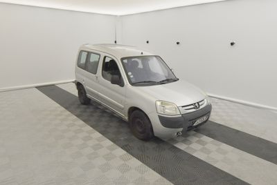 une petite camionnette blanche garée dans une pièce au sol carrelé