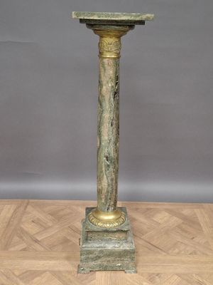 une horloge ancienne en bronze posée sur un socle, sur un parquet