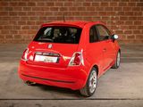 a small red car parked in front of a brick wall