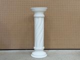 un vase blanc posé par terre devant un mur