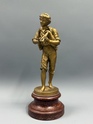 une figurine antique en bronze représentant un garçon tenant une batte de baseball