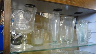 de nombreux verres et tasses posés sur une étagère en verre dans un placard