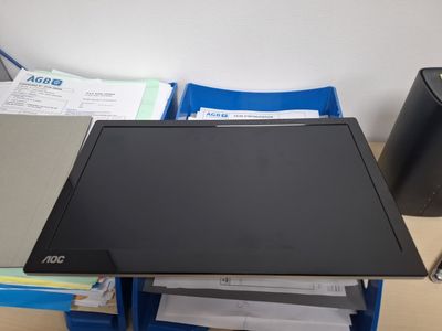 a laptop computer sitting on top of a desk next to a stack of papers