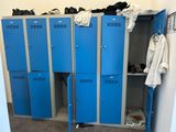 several blue lockers are lined up in a room with clothes hanging on them