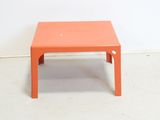 a small orange table sitting on a white floor