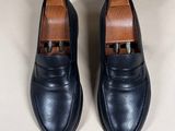 black leather loafers with gold buckles on the toes