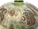 a green vase with a design on it on a white surface