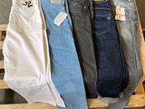 Trois paires de jeans pour homme sont posées sur une caisse en bois