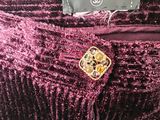 a close up of a purple dress with a gold button on it