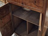 a wooden cabinet with a door open on a tile floor