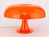 une lampe de table orange posée sur un plan de travail blanc