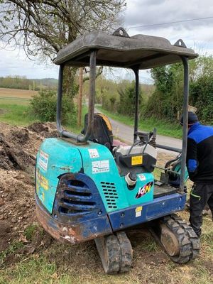 un homme debout dans la terre, à côté d'un tracteur